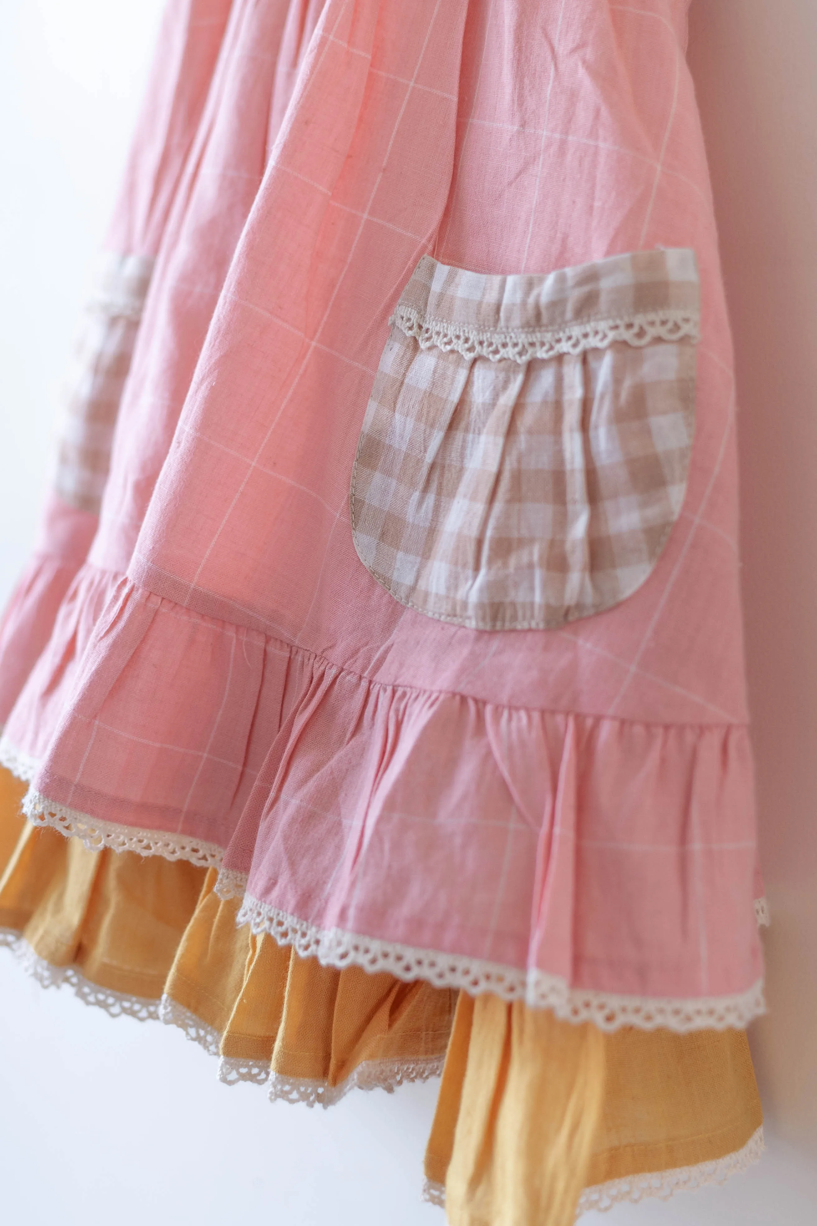 Pocketful of sunsets' sleeveless dress in peach pink with yellow frill in handwoven cotton